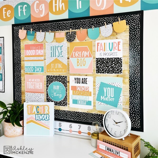 Colorful classroom posters with inspirational sayings decorate a classroom bulletin board. The posters feature a warm, calming color palette and terrazzo designs.