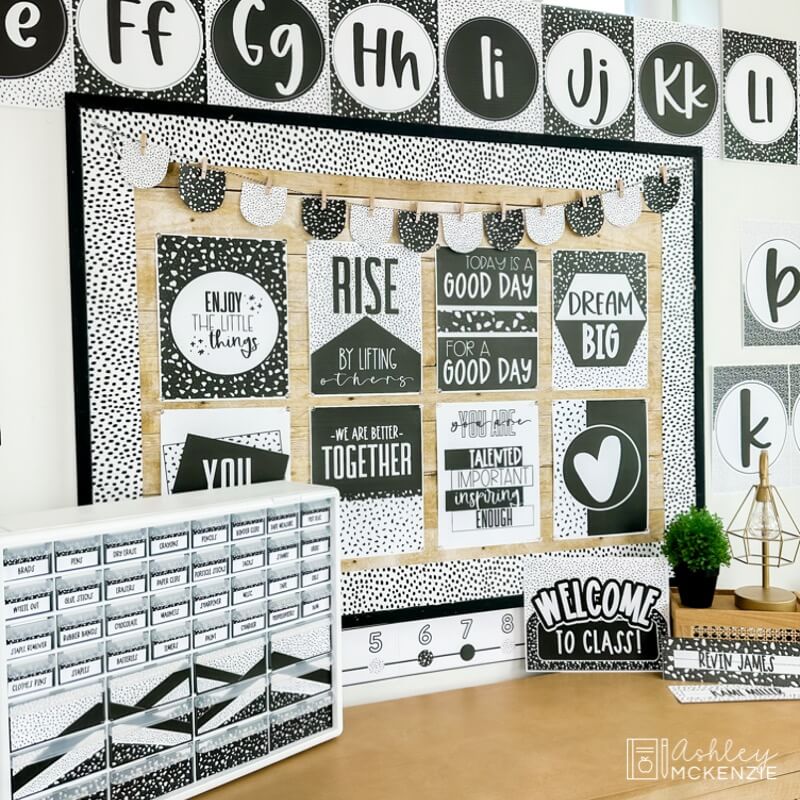 A classroom bulletin board decorated with black and white posters with positive sayings