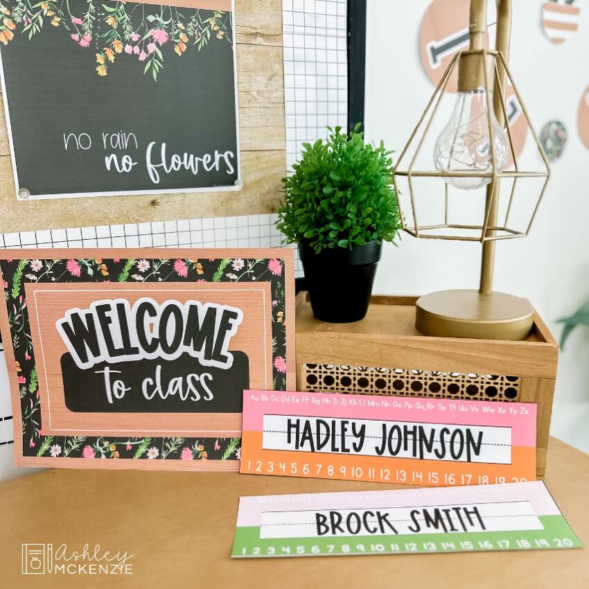 Brightly colored desk name tags are displayed next to a wildflowers themed "Welcome to class" sign