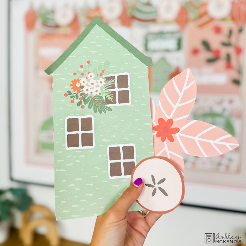 Christmas themed bulletin board decor cutouts are shown including a holiday house, poinsettia, and apple slice