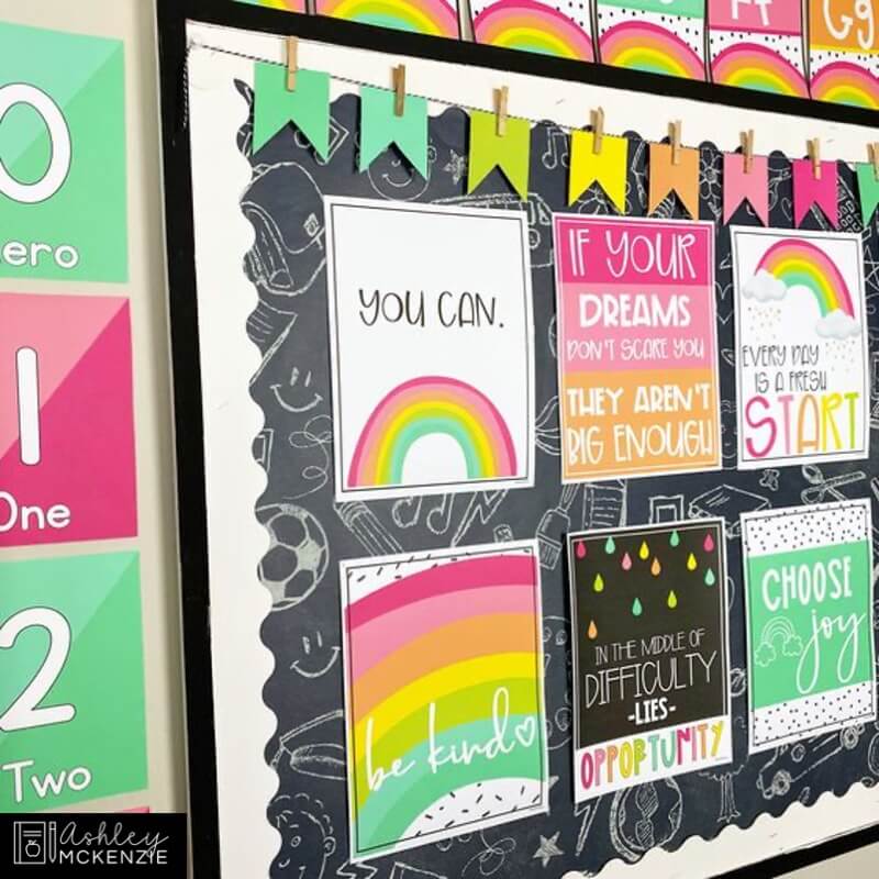 A classroom bulletin board decorated with rainbow themed classroom posters with positive sayings