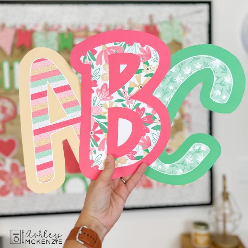 Bulletin board letters A, B, and C are being held up in colorful and bright Valentine theme patterns, primary font