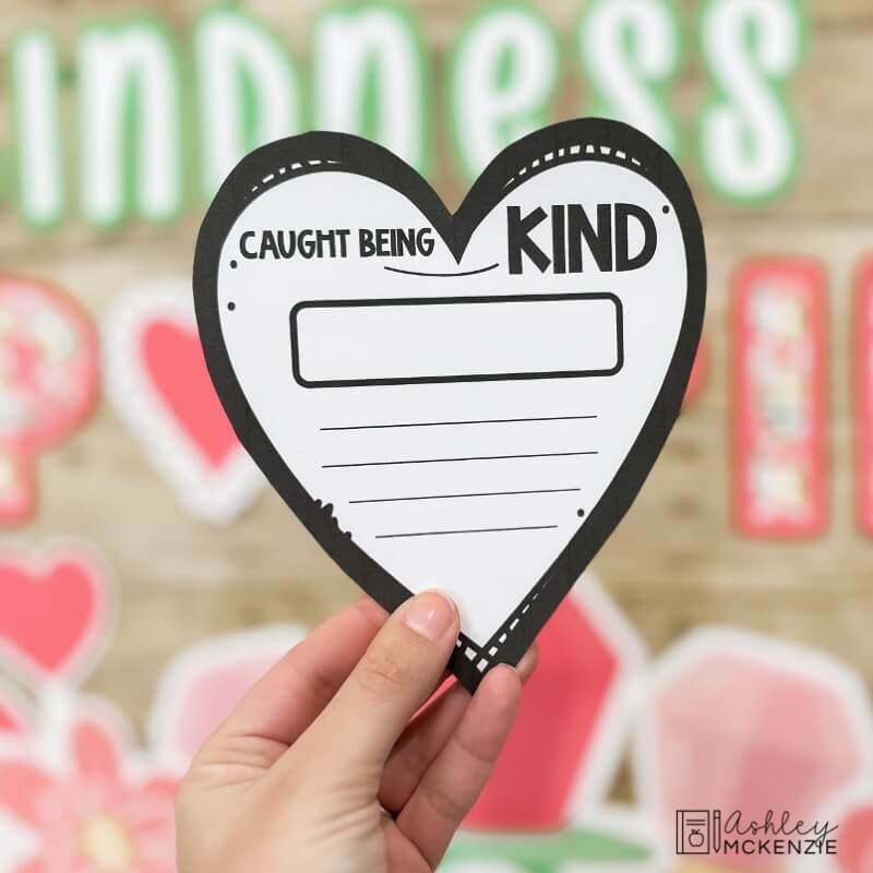 A heart shaped writing template with the text "Caught being kind" written on it