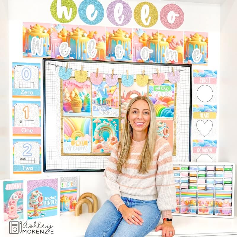 A teacher in front of a classroom wall decorated with a pastel sweets classroom decor theme